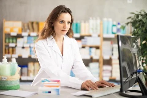 Female pharmacist checking information about medicine on computer Stock Photos