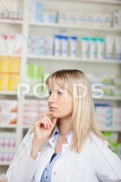 Female pharmacist with hand on chin looking away Stock Photos