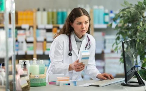 Female pharmacist looking for ointment on computer Stock Photos