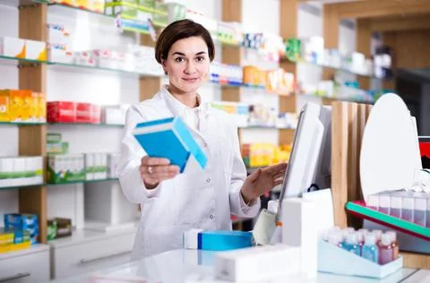 Female pharmacist offering assistance at counter in pharmacy Stock Photos