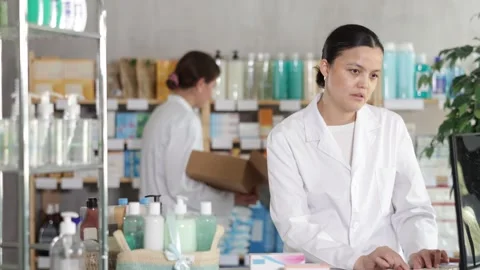 Female pharmacist processing order at computer in pharmacy Stock Footage 329541413