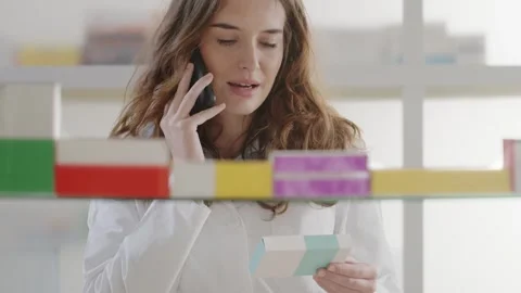 Female Pharmacist Selecting Medicine While Talking on Smartphone Stock Footage 328666253