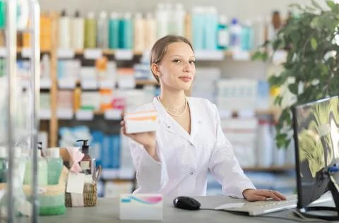 Female pharmacist working at computer offering pills Stock Photos