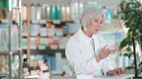 Female pharmacist working at computer in pharmacy Stock Footage 322115989