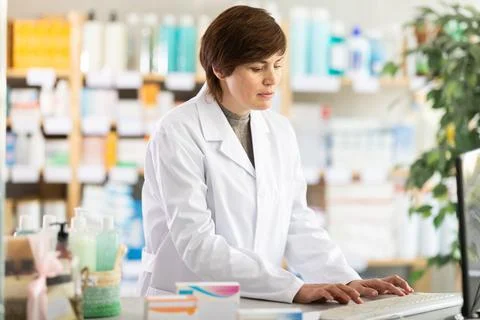 Female pharmacist working on computer at pharmacy counter Foto stock