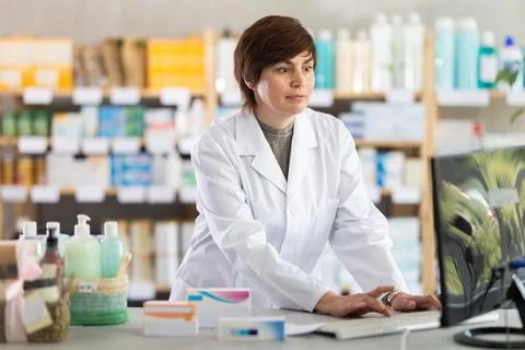 Female pharmacist working on computer at pharmacy counter Foto stock