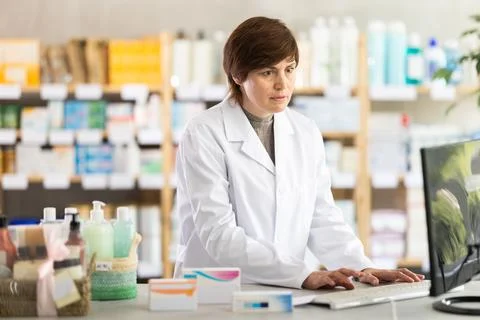Female pharmacist working on computer at pharmacy counter Foto stock