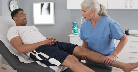 Female Physical therapist or assessing male athletes knee injury Stock Footage