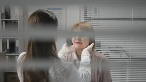 Female Physician Checking Lymph Nodes and Temperature of Elderly Woman at Clinic Stock Footage 333206183