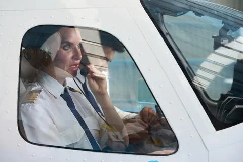 Female pilot communicating on headset during flight training Foto stock