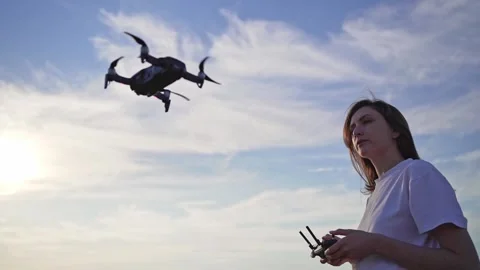 A female pilot. Control the drone against the beautiful sky at sunset. Flying Stock Footage 136659133