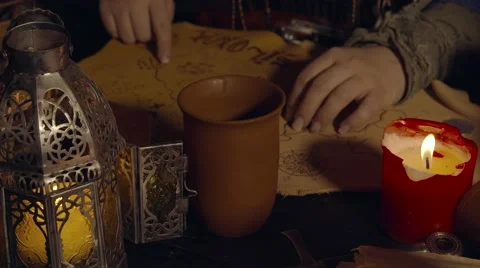 Female Pirate reading a map on a table with candles Stock Footage 50698238