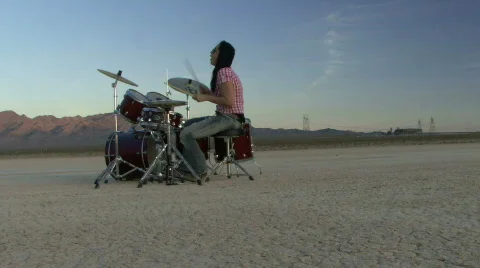 Female playing drums in desert Stock Footage