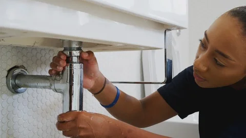 Female Plumber Working To Fix Leaking Sink In Home Bathroom Stock Footage 124569423