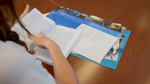 Female with ponytail reading and researching colleges Stock Footage