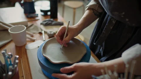 Female Potter Carving Pattern into Clay Plate with Loop Tool on Turntable Stock Footage 319227202