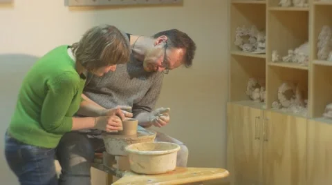 Female Potter Shows How to Mold an Edges of a Pot Student Man Leans and Looking Stock Footage 59121944
