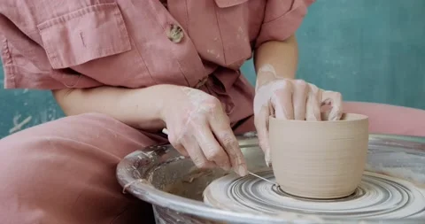Female potter sitting and makes a cup on the pottery wheel. Woman making ceramic Stock Footage 132851453