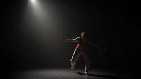 Female practicing capoeira in darkness under spotlight in studio. Stock Footage 112866560