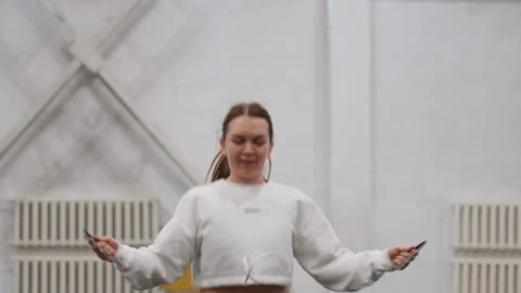 Female practicing coordinated rope skipping inside fitness center. Woman engaged Видео 345509362