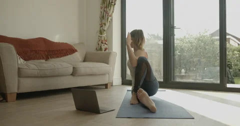 Female practicing yoga exercise at home watching video tutorial on laptop during 動画素材 141843205