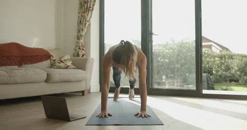 Female practicing yoga exercise at home watching video tutorial on laptop 動画素材 141843667