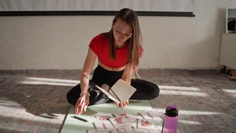 Female preparing her exercise routine with cards and journal. Woman arranging Stock Footage 342432105