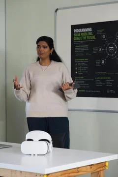 Female presenter gesturing while holding phone at whiteboard with programming Stock Photos