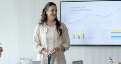 Female presenter stepping forward at table, pointing at line and bar charts, Stock Footage 342284884