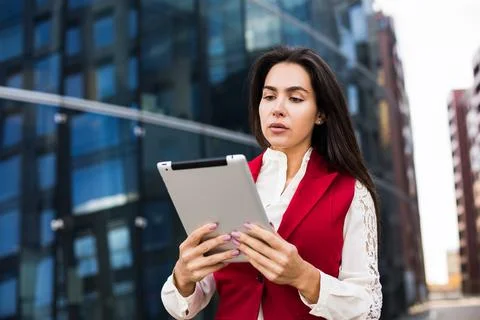 Female professional financier checking e-mail on portable touch pad while sta Stock Photos