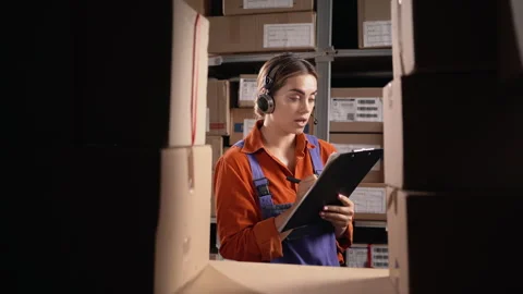 Female professional operator wearing headset standing next to shelf, counting Stock Footage 249866277