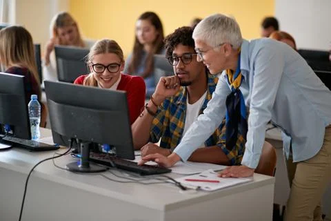 Female professor correcting students errors at an informatics lecture Stockfoto's