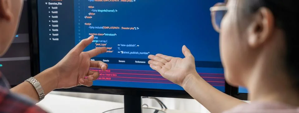 Female programer explain while pointing code displayed on computer. Burgeoning. Stock Photos