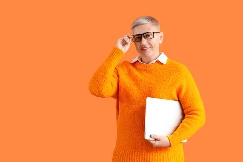 Female programmer with laptop on orange background Stock Photos