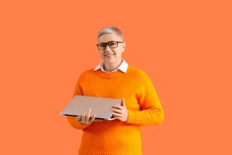 Female programmer with laptop on orange background Foto stock