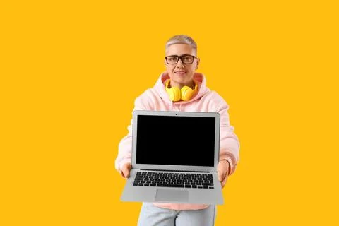 Female programmer with laptop on yellow background Stock-Fotos