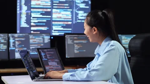 Female Programmer Looking   And Writing Code By A Laptop Using Multiple Monitors Stock Footage 244426854