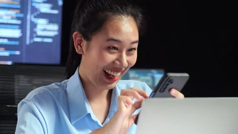 Female Programmer Looking At phone While Code Laptop Using Multiple Monitors Stock Footage 244422044