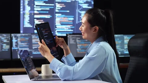 Female Programmer Looking  Writing Code By A Laptop Using Multiple Monitors Stock Footage 244426825