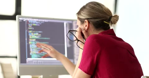Female programmer reviews source code on computer screen Stock Footage 308877665