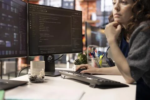 Female programmer seen typing code for a user interface design on dual monitors 写真素材
