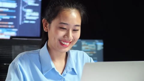 Female Programmer Smiling While Writing Code By A Laptop Using Multiple Monitors Stock Footage 244422532