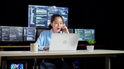 Female Programmer Talking Smartphone While Writing Code Laptop Multiple Monitors Video stock 244423304