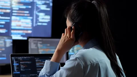 Female Programmer Talking Smartphone Writing Code Laptop Using Multiple Monitors Stock Footage 244425585