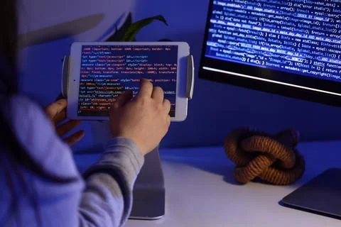 Female programmer testing code on tablet computer in office at night, closeup Foto stock