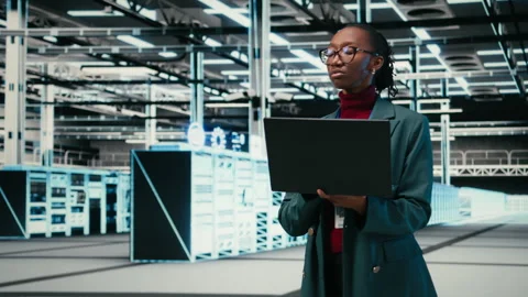 Female programmer walking in data center engineer uses AR simulation and laptop Stock-Footage 329452963