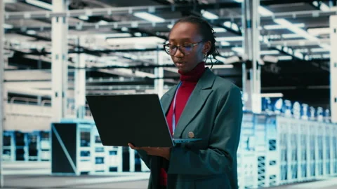 Female programmer walking in data center engineer uses AR simulation and laptop Stock Footage 329650856