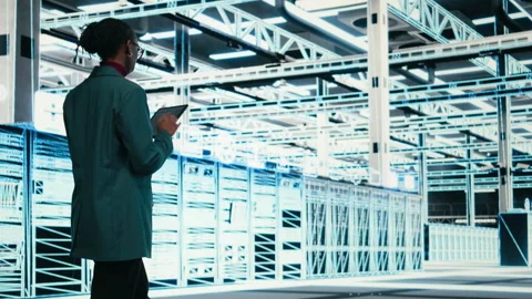 Female programmer walking in data center using tablet to write code Stock Footage 329716534