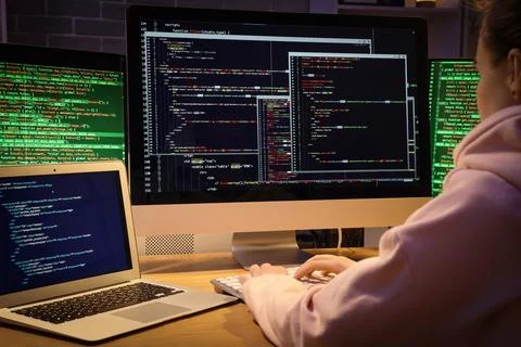 Female programmer working with computer in office at night, back view Stock Photos
