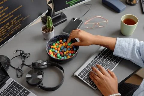 Female Programmer Working at Desk and Eating Candy Stock Photos